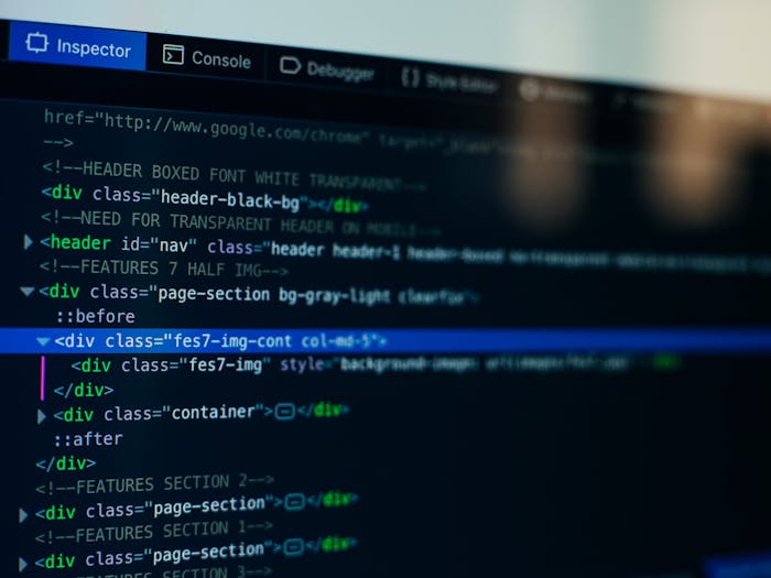 A close-up photo of a computer screen showing HTML code in the 'Inspector' panel of a browser's developer tools. The code is on a dark background, and one 'div' tag is highlighted in blue, indicating it is selected.