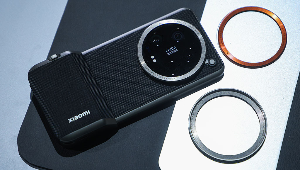 Xiaomi smartphone with a Leica-engineered circular camera module, placed on a display table alongside two interchangeable lens filters, designed to resemble a high-end compact digital camera