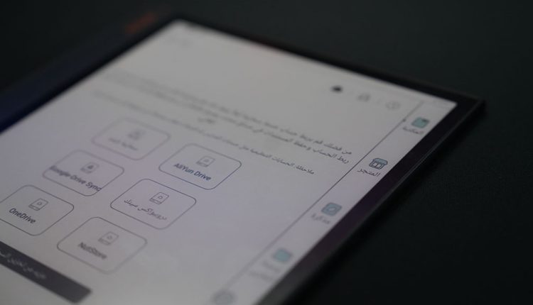 A close-up, angled shot of a Boox Note Air3 C e-reader tablet displaying an interface in Arabic. The screen shows options for connecting to cloud storage services like "Google Drive Sync," "AliYun Drive," and "OneDrive," with other menu icons visible on the right sidebar. The device rests on a dark surface.