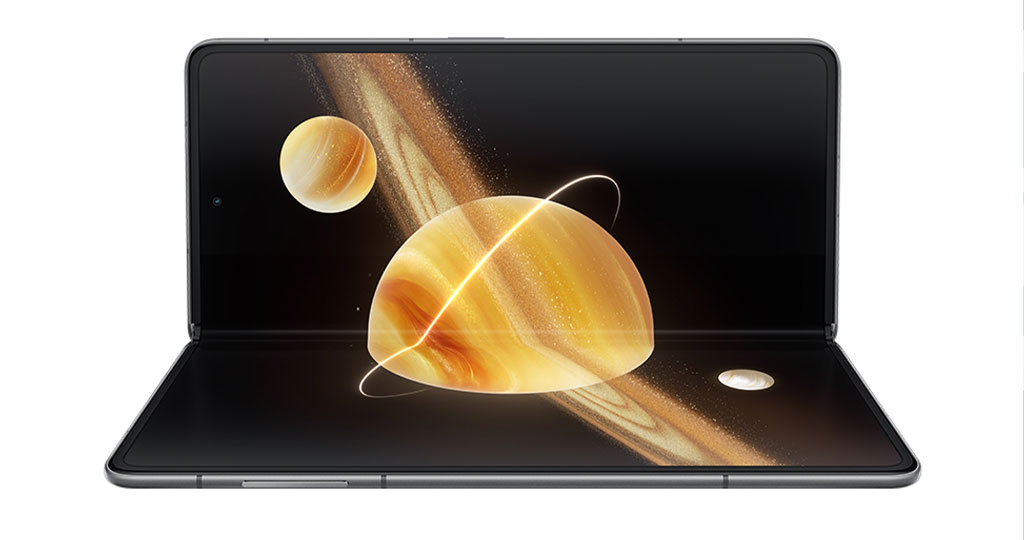 **Alt text (English):** The HONOR Magic V3 foldable smartphone displayed in a half-opened, laptop-like position. The screen shows a vivid 3D visual of golden planets and space rings, highlighting the immersive display and hinge flexibility. The image emphasizes the large, seamless folding screen and the device’s futuristic interface powered by MagicOS. 