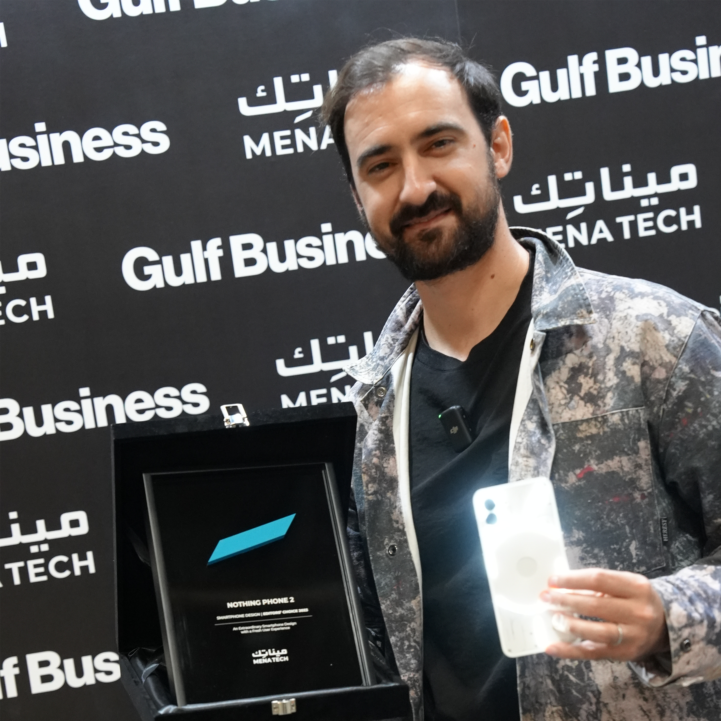 A proud representative showcasing the Nothing Phone 2 alongside the MENA Tech Editors' Choice 2023 award for best smartphone design.